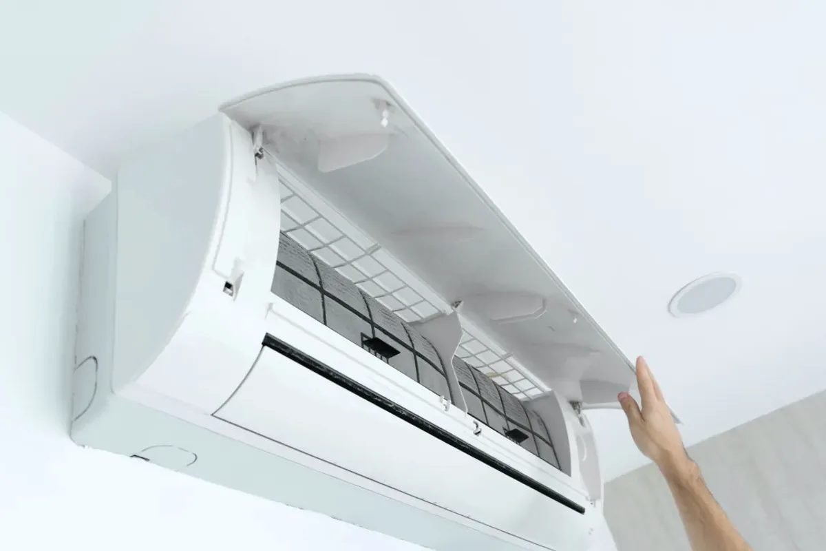 Hand opening the cover of a wall-mounted ductless air conditioner